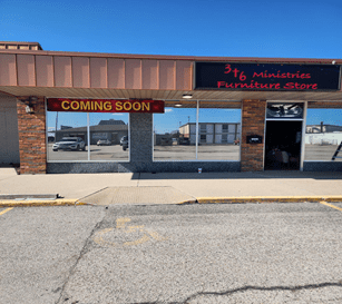 Empty storefront with 'Coming Soon' sign under clear blue sky.